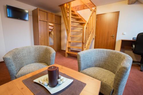 a living room with a table and chairs and a staircase at Penzion U řeky in Vojkovice
