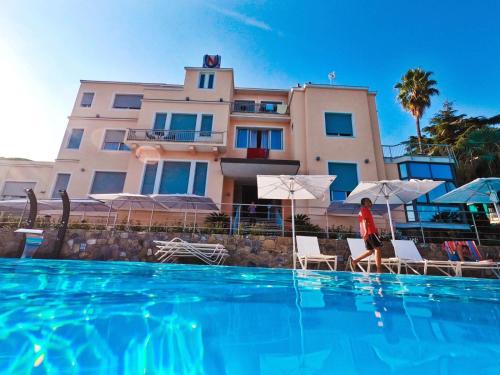 eine Person, die neben einem Pool vor einem Gebäude steht in der Unterkunft Hotel Napoleon in Sanremo