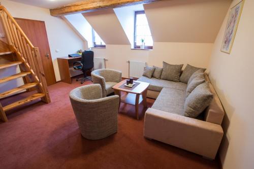 a living room with a couch and two chairs at Penzion U řeky in Vojkovice