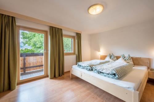 ein Schlafzimmer mit einem Bett und einem großen Fenster in der Unterkunft Jogglanderhof - Hochwilde in Moos in Passeier