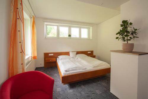 ein Schlafzimmer mit einem Bett und einem roten Stuhl in der Unterkunft Hotel Garni Brigitte in Bürserberg