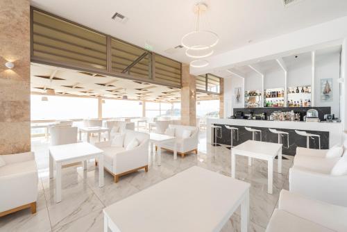 ein Restaurant mit weißen Tischen und weißen Stühlen in der Unterkunft White Rock of Kos Hotel - Adults only in Kefalos
