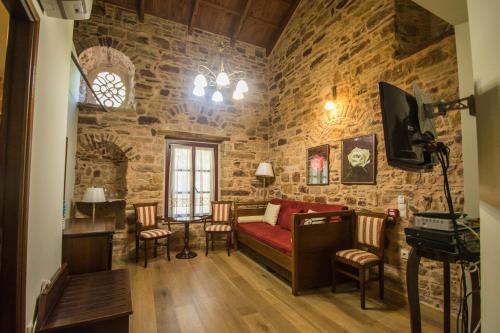 a living room with a red couch in a stone wall at Archontiko Riziko in Kambos