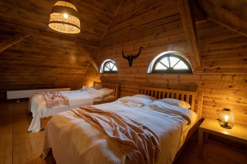 a bedroom with two beds in a log cabin at Siedlisko Szymonka in Ryn