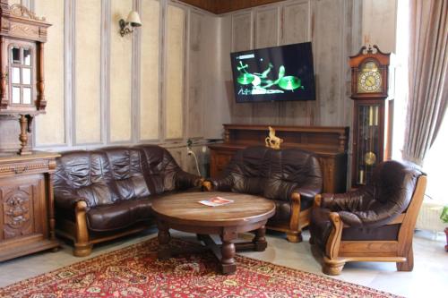 a living room with leather furniture and a clock at Park Hotel Ivailo in Veliko Tŭrnovo