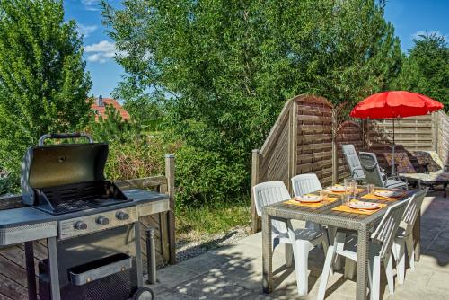 a patio with a table and a grill and a table and chairs at Appartement privatif type chalet cosy et calme in Métabief