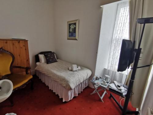 
a bedroom with a bed, chair and a television at Park Guest House in Inverness
