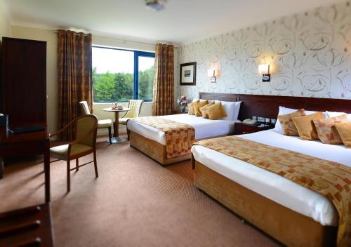 a hotel room with two beds and two tables at Kiltimagh Park Hotel in Kiltimagh
