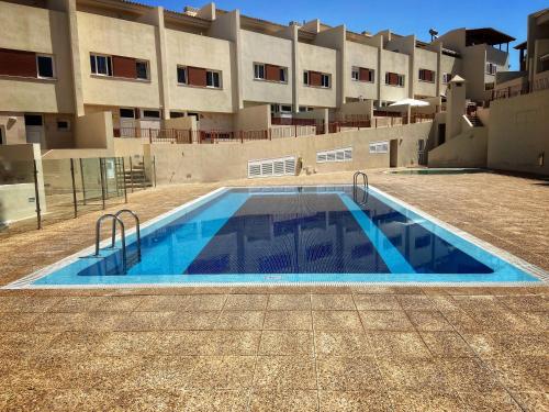 an empty swimming pool in front of a building at Los Cristianos 4 Bed Townhouse in Los Cristianos