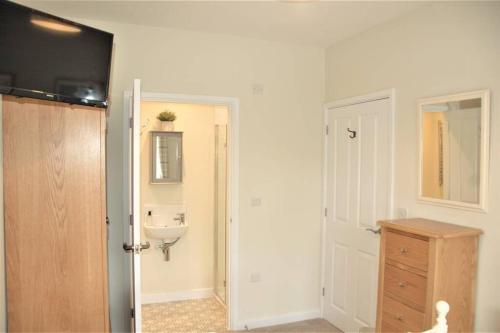 ein Badezimmer mit einem Waschbecken, einem WC und einem Spiegel in der Unterkunft Bar Lodge at Broxa in Long Riston