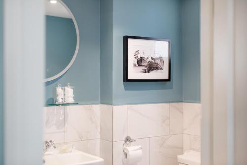 a bathroom with blue walls and a picture on the wall at Moore House in Hastings