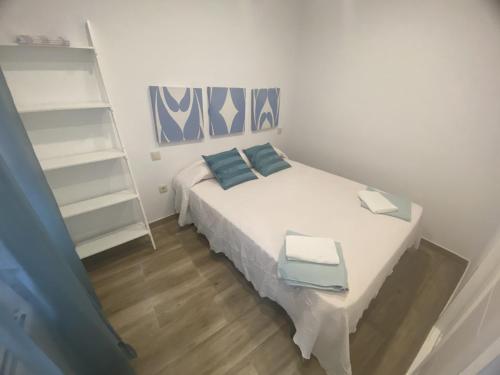 a small bedroom with a white bed with blue pillows at La Plaza Vieja in Cuevas del Valle