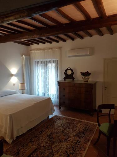 a bedroom with a bed and a dresser and a window at La Casa dei Vezzi in San Gimignano