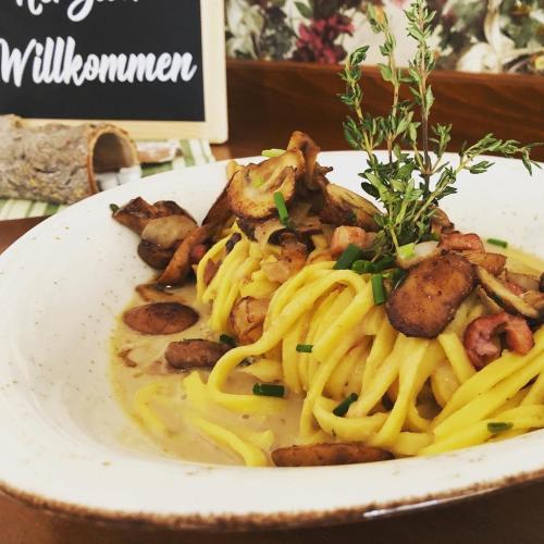 a plate of pasta with sausage and mushrooms on a table at Landhotel Witte-König in Garrel