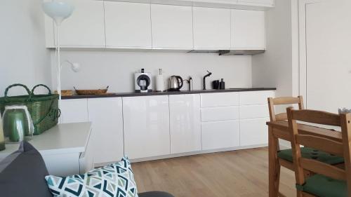a white kitchen with white cabinets and a wooden floor at Morskie Wzgórze Apartamenty in Mechelinki
