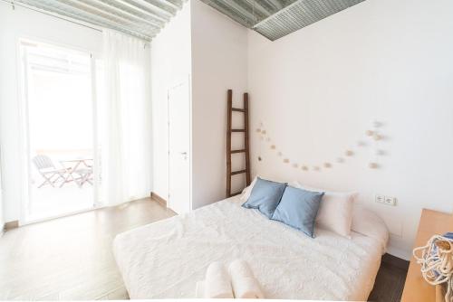 a white bedroom with a large bed with blue pillows at Mirador Torre de la Garrofa in Almería