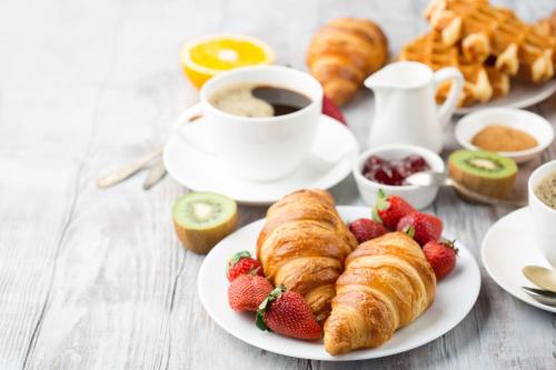 a table with plates of croissants and strawberries and a cup of coffee at Parrot Cottage at Viking Hill - Love Beach in Nassau