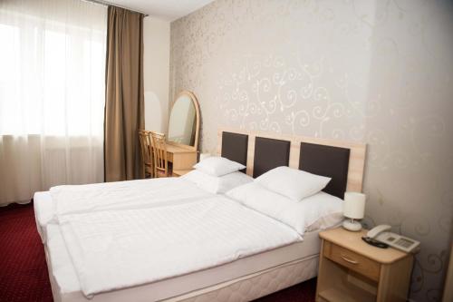 a bedroom with a white bed and a phone on a table at Hozam Wellness és Apartman in Szolnok