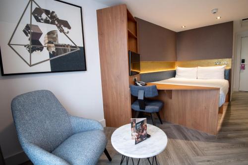 a hotel room with a bed and a chair and a desk at Roomzzz London Stratford in London