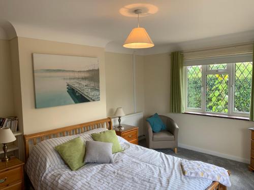 a bedroom with a bed and a chair and windows at Eastfield B & B in Ringwood