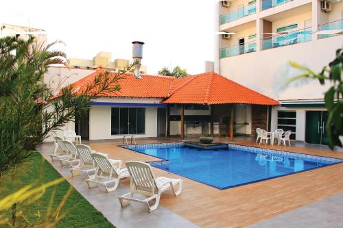 a pool with a bunch of chairs next to a building at PARANÁ PALACE HOTEL in Campo Mourão