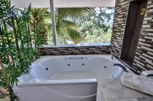 a large white bath tub in a bathroom with plants at Hotel 212 Olympos in Olympos