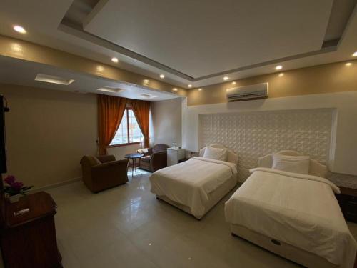 um quarto de hotel com duas camas e uma sala de estar em Hotel Danat Al Khaleej em Ḩilf