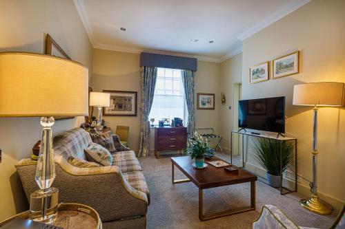 sala de estar con sofá y TV en The Rutland Arms Hotel, Bakewell, Derbyshire, en Bakewell