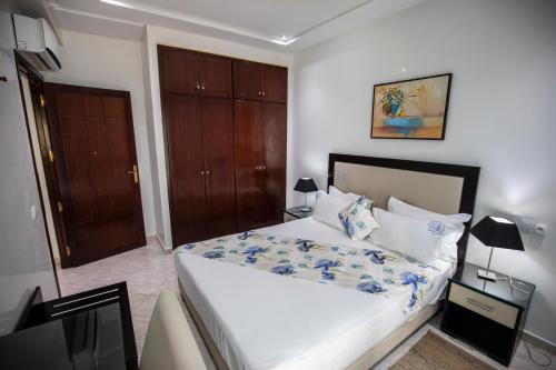 a bedroom with a large white bed and a door at Appart Hotel Rania in Tangier