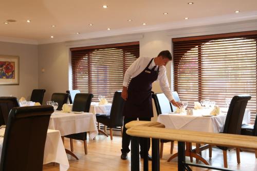 a man is standing in a dining room with tables at Widnes Halton Everglades Park Hotel in Widnes