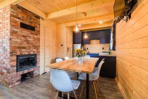 a dining room with a wooden table and a fireplace at CHATY TRZY in Solina