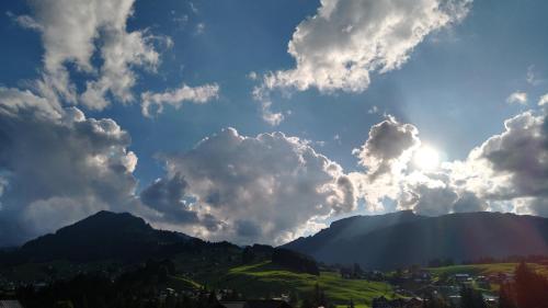 a cloudy sky with the sun shining on a mountain at Hotel Almhof Rupp in Riezlern