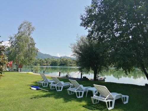 a row of white chairs sitting on the grass near a lake at Vikendica Marija, Culine in Mali Zvornik