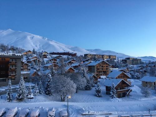 uma cidade coberta de neve com uma montanha ao fundo em Appartement traversant résidence chaput 2 - 2 pièces - 6 personnes - vue sur front de neige em La Toussuire
