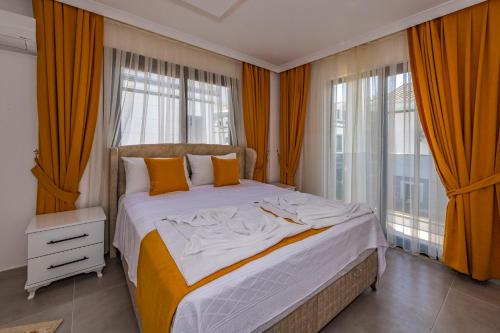 a bedroom with a large bed with orange curtains at Salkım- 4 Bedroom Holiday Villa in Oludeniz in Fethiye