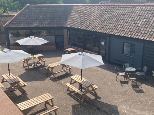 a group of picnic tables and umbrellas in front of a building at Swan View, Oulton Broad in Lowestoft