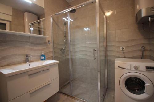 a bathroom with a shower and a washing machine at Apartment ZO-NA in Povile