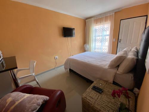 Un dormitorio con una cama, un sofá y una silla. en Mankweng lodge, en Polokwane