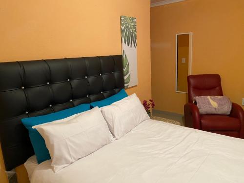 a bedroom with a bed with a black headboard and a red chair at Mankweng lodge in Polokwane