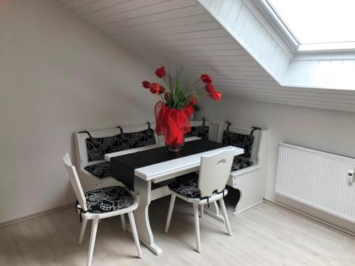 uma sala de jantar com uma mesa com um vaso de flores vermelhas em Ferienwohnung Taunus im Grünen Obergeschoss em Langgöns