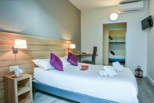 Habitación de hotel con 2 camas con almohadas moradas en Logis Hôtels Gnàc é Pause, en Saint-Lon-les-Mines