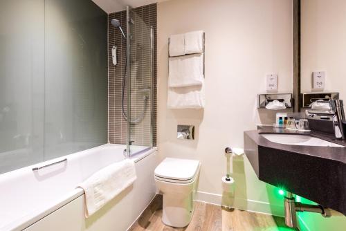 a bathroom with a toilet and a sink and a tub at Holiday Inn Runcorn M56 Junction 12, an IHG Hotel in Runcorn