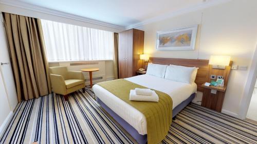 um quarto de hotel com uma cama e uma cadeira em Holiday Inn Runcorn M56 Junction 12, an IHG Hotel em Runcorn