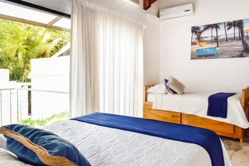 a bedroom with two beds and a large window at Casa Guarumo Carrillo in Carrillo