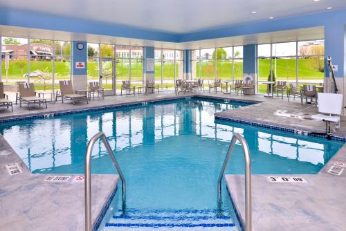 a large swimming pool in a hotel with tables and chairs at Holiday Inn Express & Suites Madison, an IHG Hotel in Madison