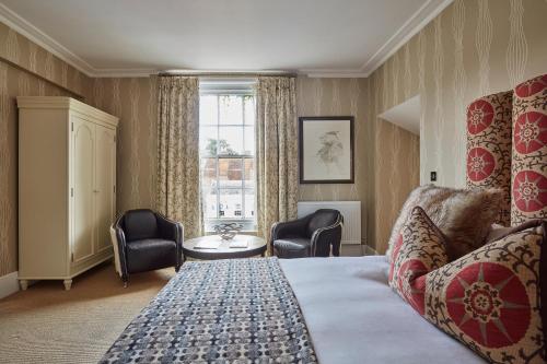 a hotel room with a bed and chairs and a window at Angel Hotel in Bury Saint Edmunds