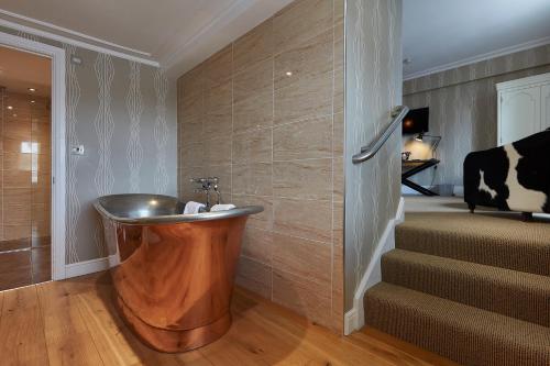 a bathroom with a copper tub next to a staircase at Angel Hotel in Bury Saint Edmunds