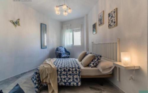 1 dormitorio con 1 cama con manta azul y ventana en Villa gaviota, en Almuñécar