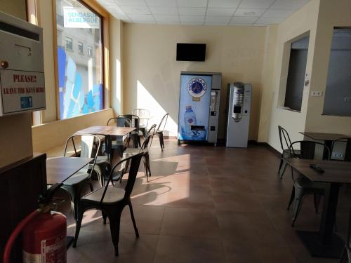 a restaurant with tables and chairs and a drink machine at Senda Sur in Porriño