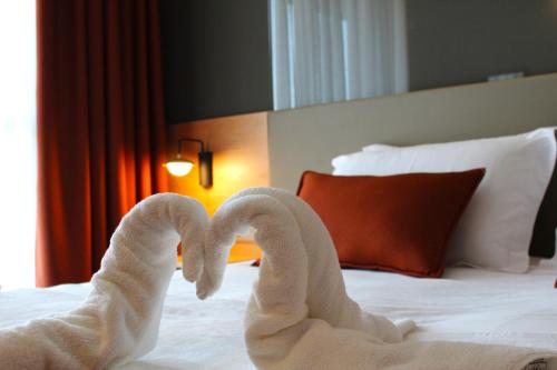 two towel swans making a heart on a bed at YURDAKUL HOTEL in Barbaros